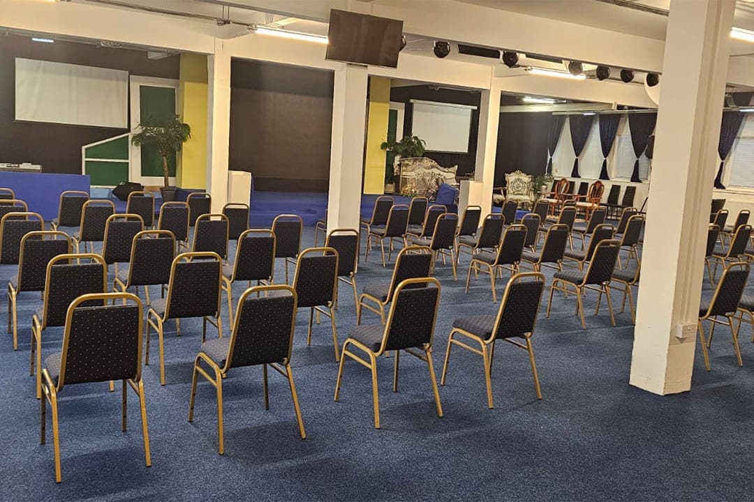 The Grand Conference Hall with rows of gold framed chairs on a blue carpet, facing the stage.