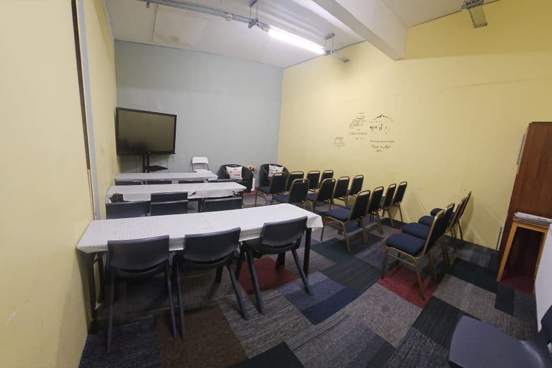 The Executive Meeting Room with a long table, black chairs and a wall mounted screen.